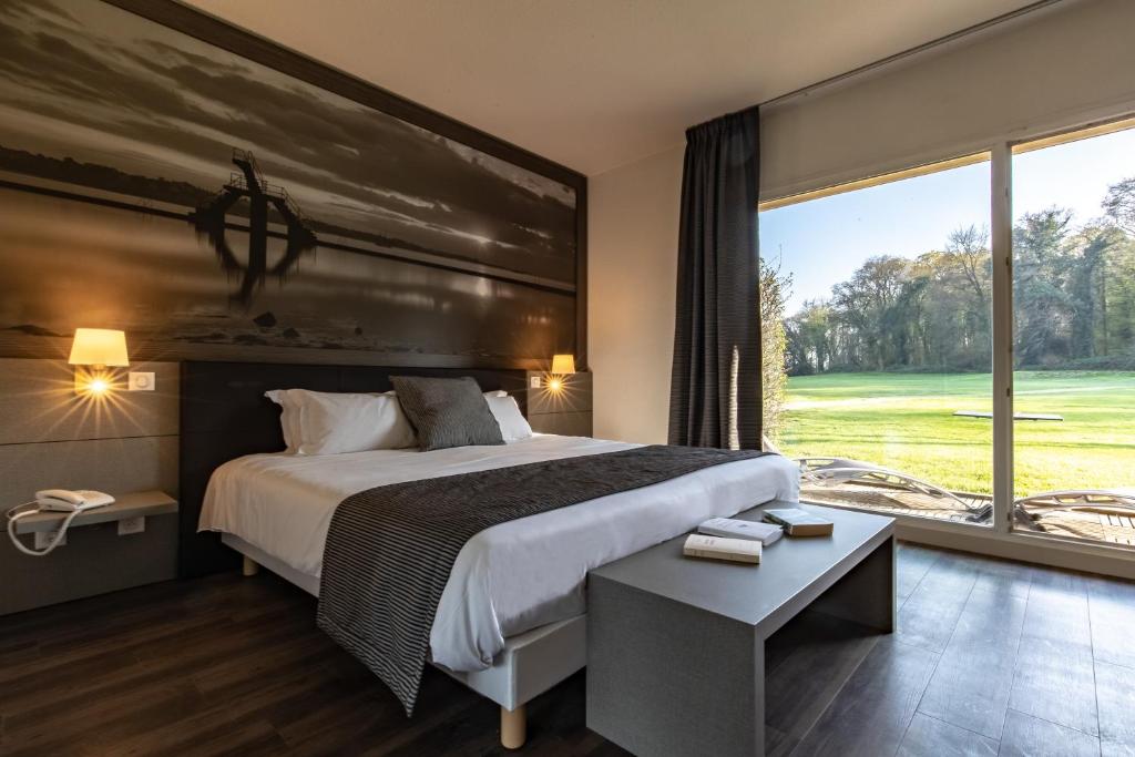 a bedroom with a large bed and a large window at Saint Malo Golf Resort in Le Tronchet