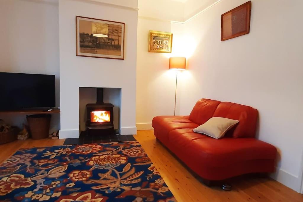 a living room with a red couch and a fireplace at Stylish Victorian House in Watford