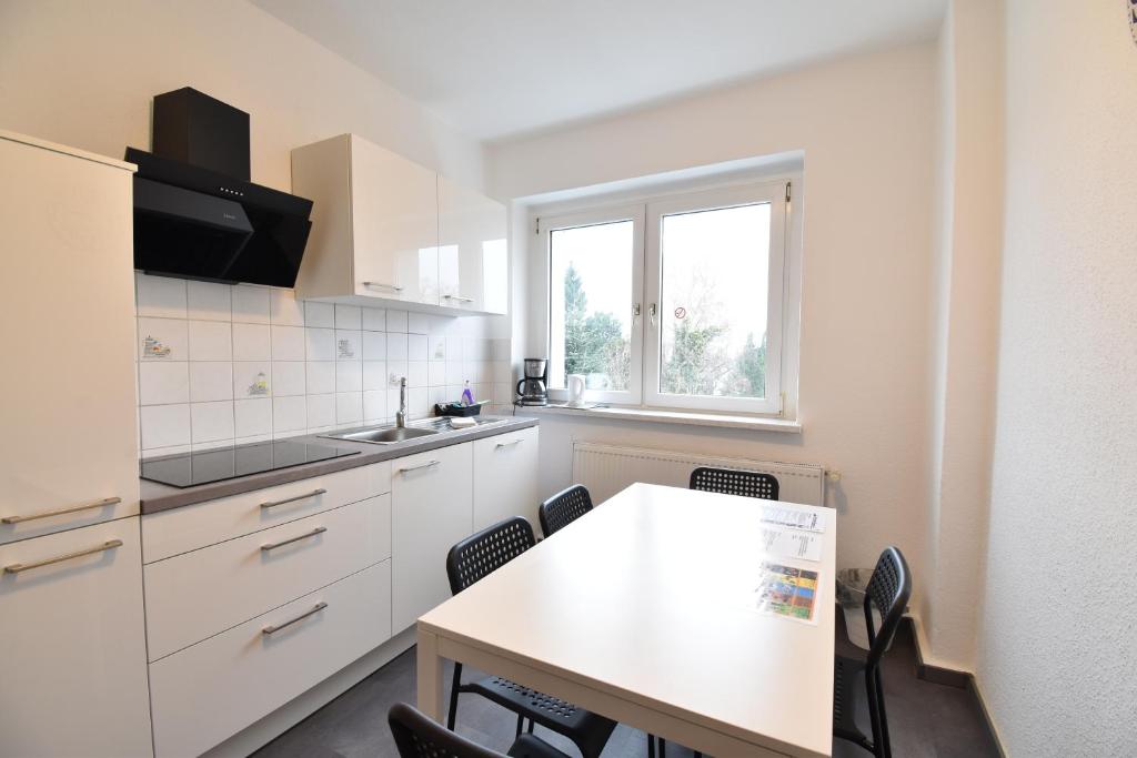 una cucina con armadi bianchi, tavolo e sedie di CoreRooms - Apartment Bochum Wattenscheid a Bochum