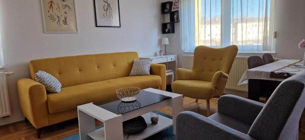 uma sala de estar com um sofá amarelo e duas cadeiras em CENTRUM with private parking em Virovitica