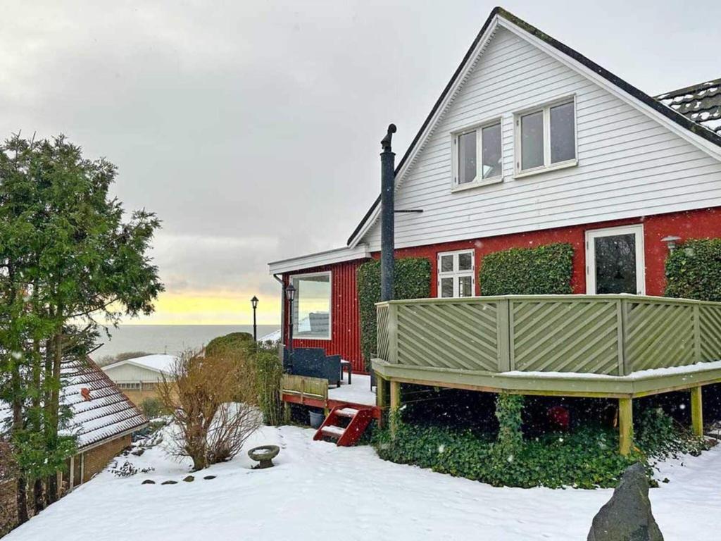 a red house with a snow covered yard at Holiday home Rønne VI in Rønne
