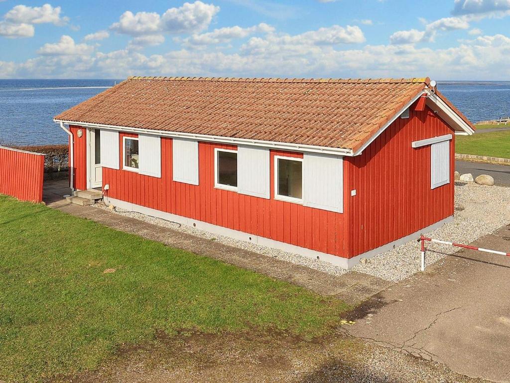 un edificio rojo y blanco junto al océano en Holiday home Bogense XLVI, en Bogense