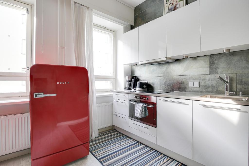 een rode koelkast in een keuken met witte kasten bij Kotimaailma Apartments Kamppi - studio for 2 in Helsinki