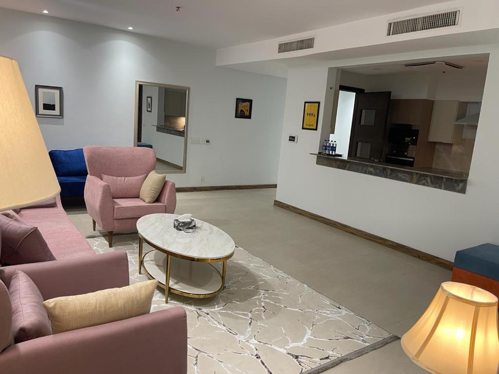 a living room with pink chairs and a table at Gold crest Mall & Residence in Lahore