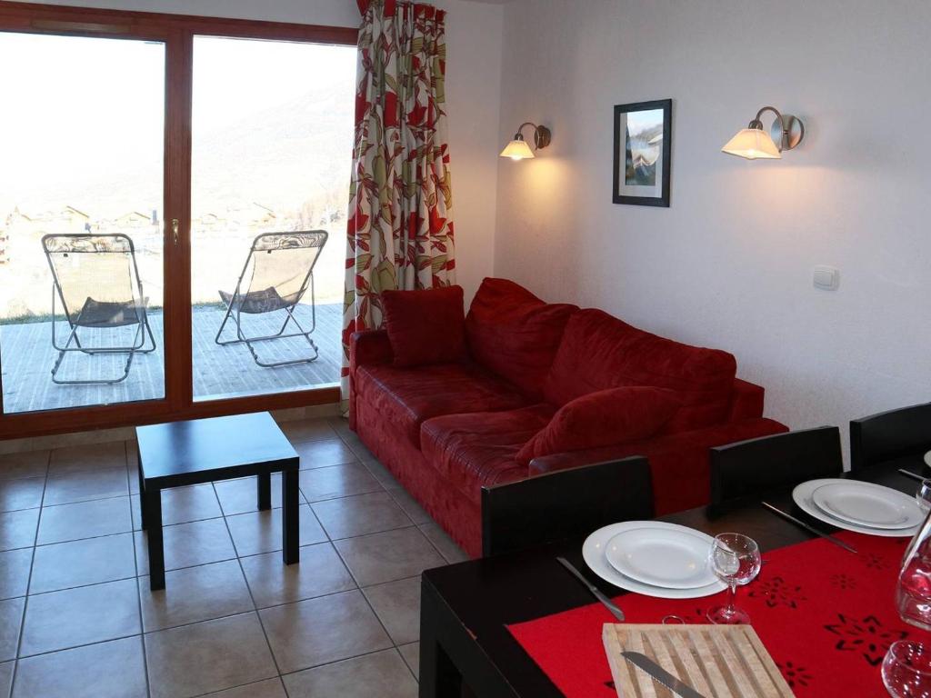 ein Wohnzimmer mit einem roten Sofa und einem Tisch in der Unterkunft Chalet Les Orres, 3 pièces, 6 personnes - FR-1-322-149 in Les Orres