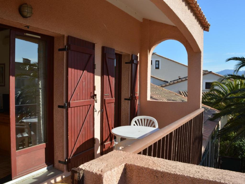 d'un balcon avec une porte rouge et une table. dans l'établissement Appartement Saint-Cyprien, 2 pièces, 6 personnes - FR-1-225D-25, à Saint Cyprien Plage