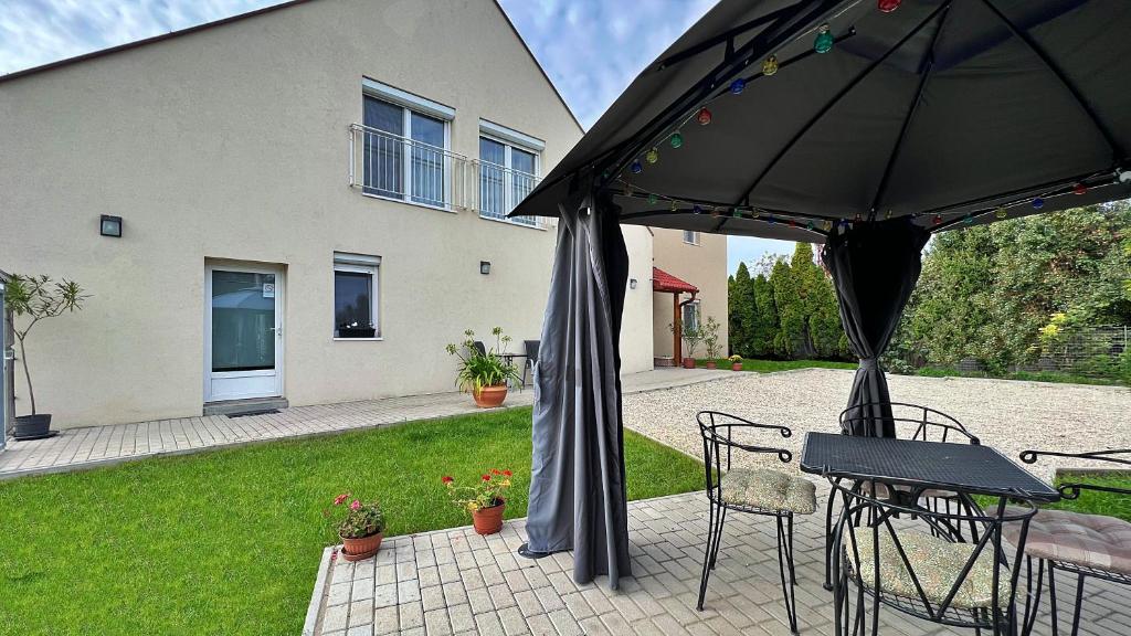 une terrasse avec une table, des chaises et un parasol dans l'établissement Gardencity Apartmanház, à Győr