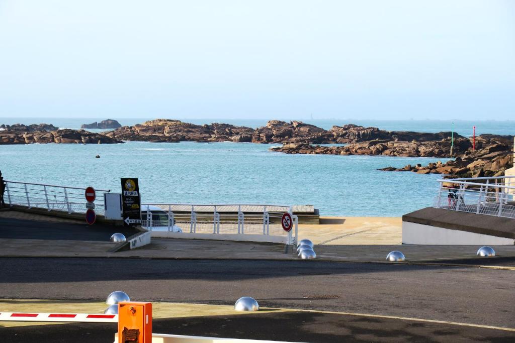 une vue sur une étendue d'eau à côté d'une route dans l'établissement Appartement Duplex VUE MER face à la plage du Coz-Pors à TREGASTEL - Réf 608, à Trégastel