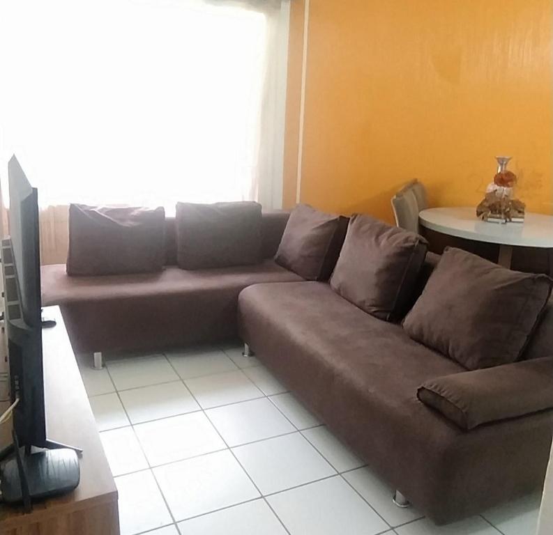 een woonkamer met een bank en een tv bij ApartamentoTop Praia Jacarecica 200mts da praia in Maceió