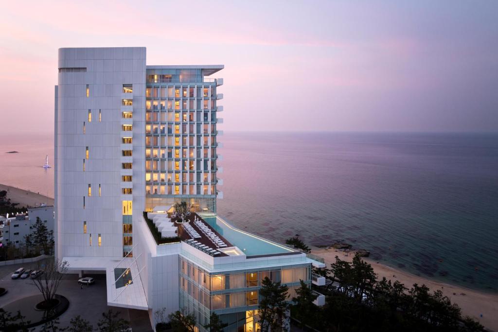a tall building next to the ocean at dusk at SEAMARQ HOTEL in Gangneung