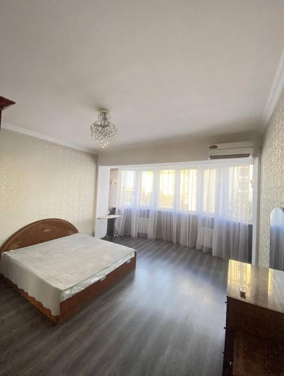 een slaapkamer met een bed en een groot raam bij Уютный уголок в центре города in Bisjkek
