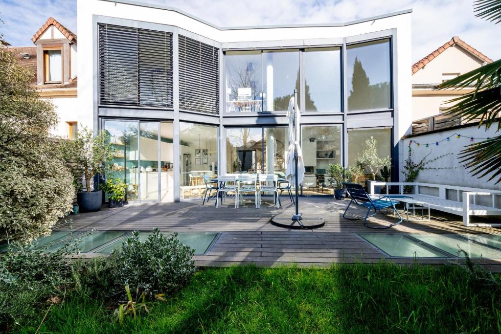 Cette grande maison en verre dispose d'une terrasse et d'une table. dans l'établissement Villa Corneille - Welkeys, à Versailles