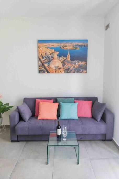 een paarse bank met kleurrijke kussens in de woonkamer bij Centeraly Located Cozy Apartment in Gzira in Il- Gżira