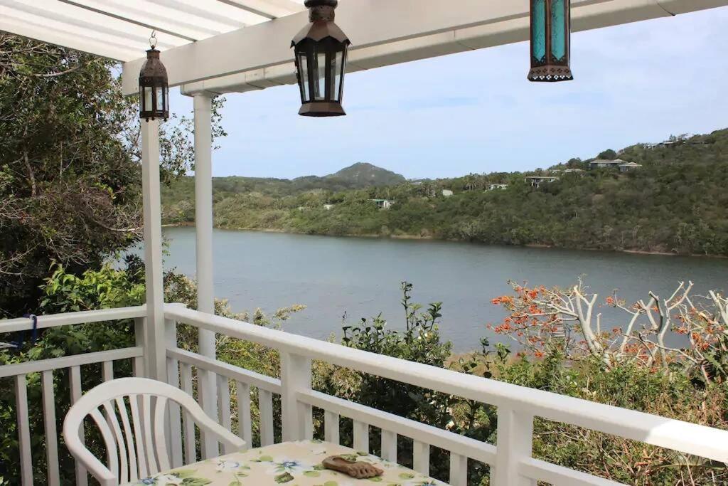 a white porch with a view of a river at Weaver Cottage in Chintsa East on the Wild Coast in Cintsa