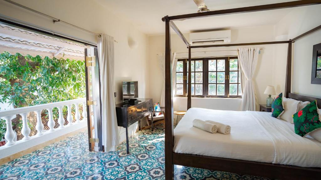 a bedroom with a canopy bed and a balcony at Villa Olive goa ( OV private pool villas ) in Mapusa
