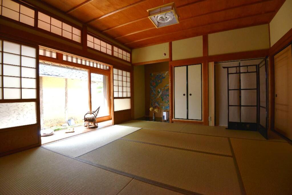an empty room with a large window and a door at countryside stay ゲストハウスもらいもん in Kanaya