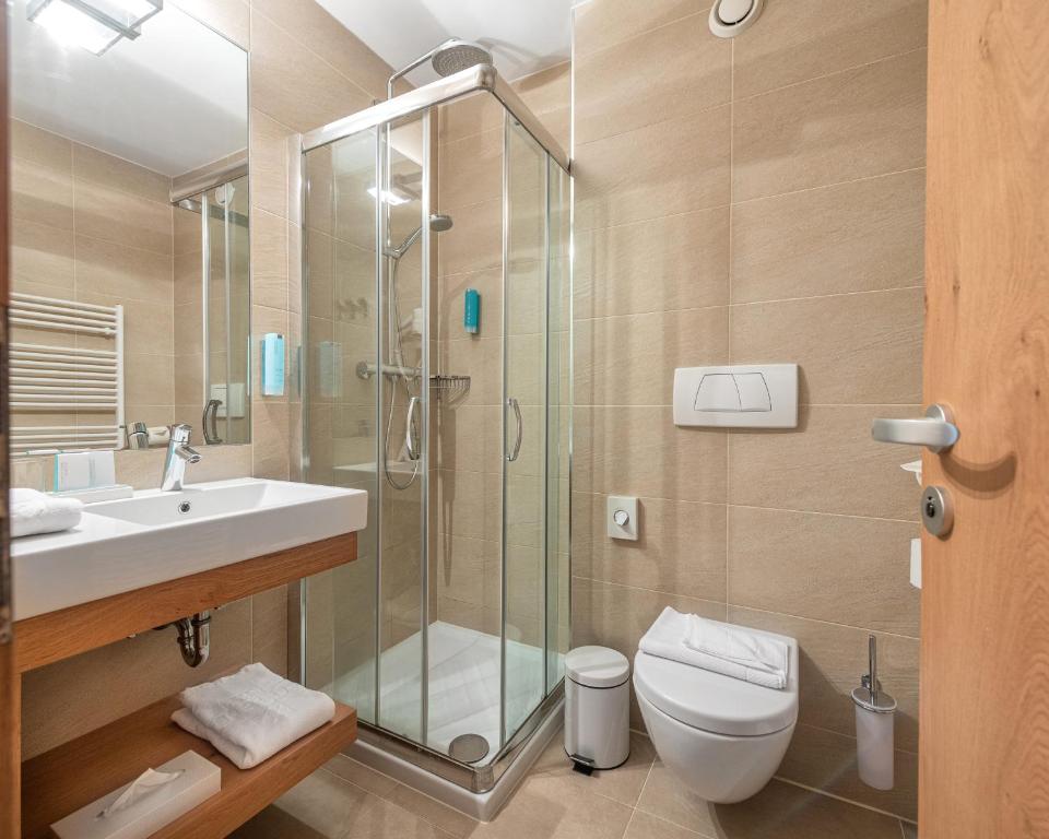 a bathroom with a shower and a toilet and a sink at Seehotel Urban in Bodensdorf