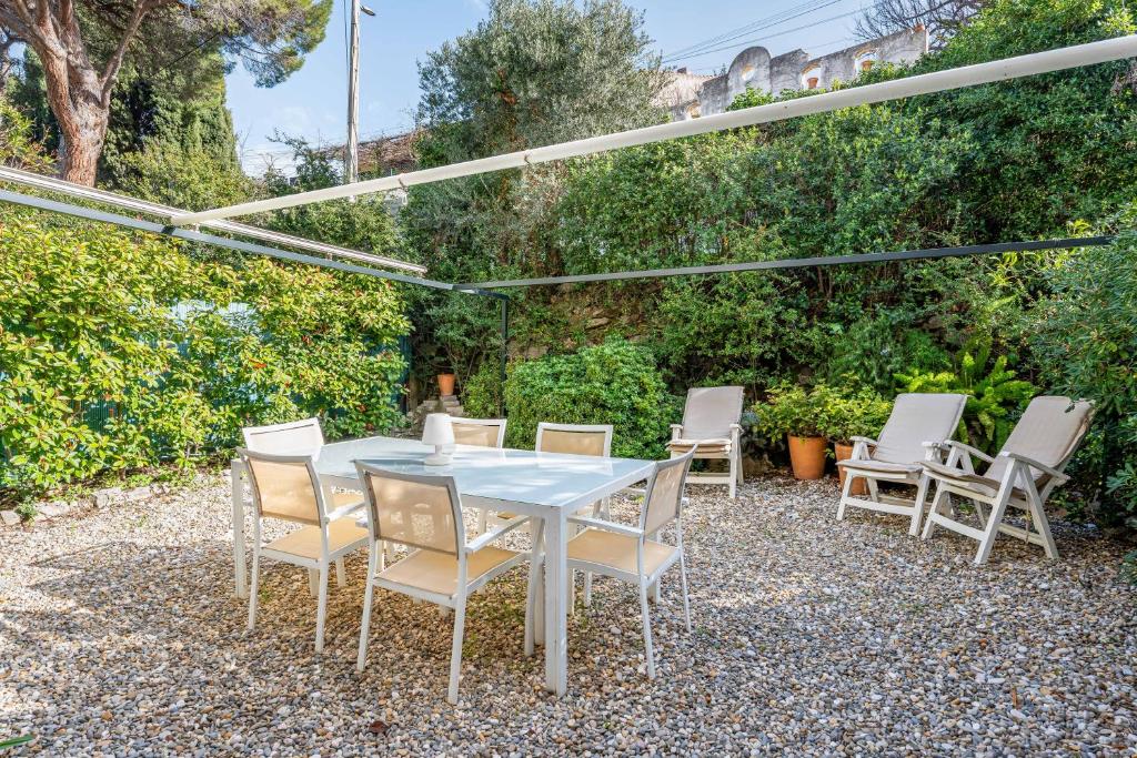 une table et des chaises blanches sur une terrasse en gravier dans l'établissement Le Marignan par Dodo à Cassis, à Cassis