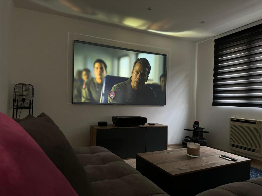 a living room with a flat screen tv on the wall at Jolie maison avec Salon Cinéma in Mouy