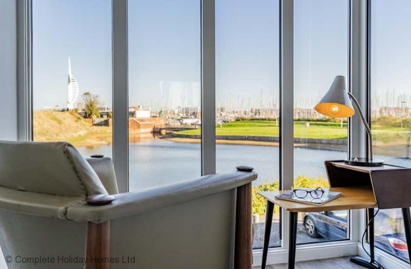 a living room with a chair and a table and windows at Rampart View in Gosport