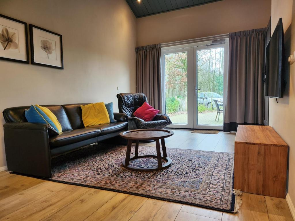 a living room with a leather couch and a coffee table at Landhuis de heibloem in Heythuysen