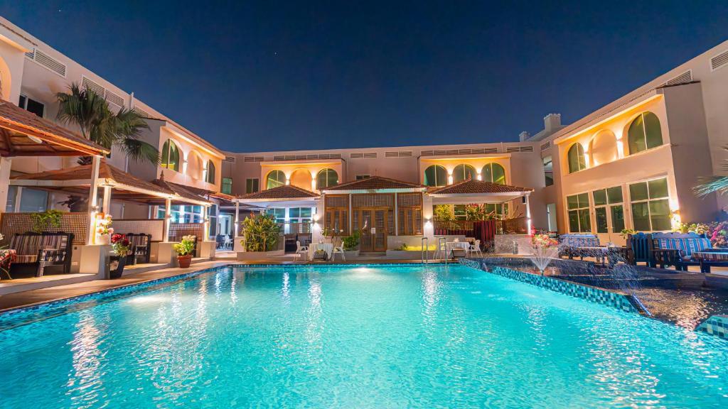 a swimming pool in front of a building at night at Al Dar Inn Hotel Apartment in Ras al Khaimah