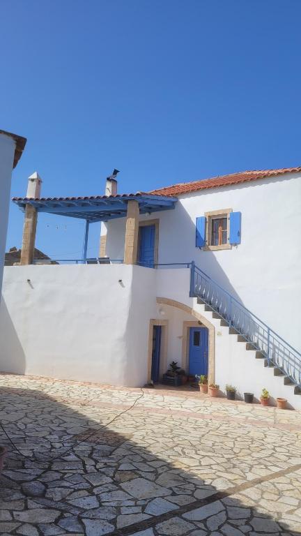 a white building with a blue door and stairs at KASTRI in Kythira