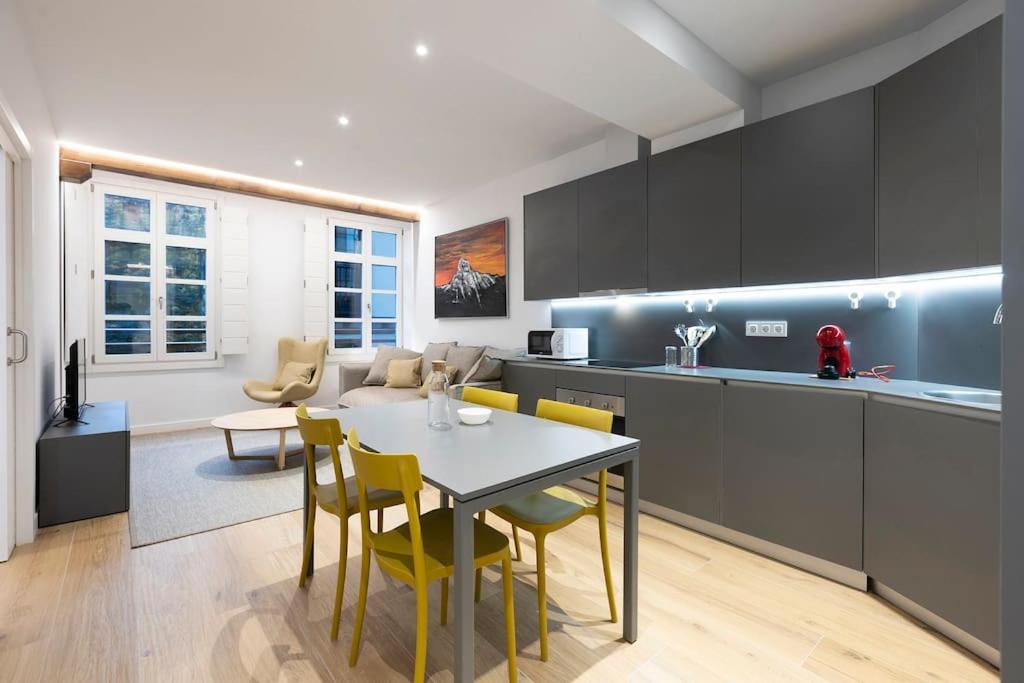 a kitchen with a table and yellow chairs in a room at Alde-zahar. Basquenjoy in Hondarribia