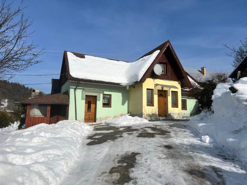 ein Haus ist mit Schnee bedeckt mit einer Auffahrt in der Unterkunft Chatka Hanka in Terchová
