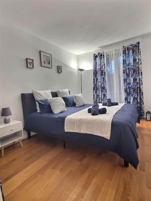 Una gran cama azul en una habitación con suelo de madera. en Appartement a proximité aéroport paris Orly en Antony