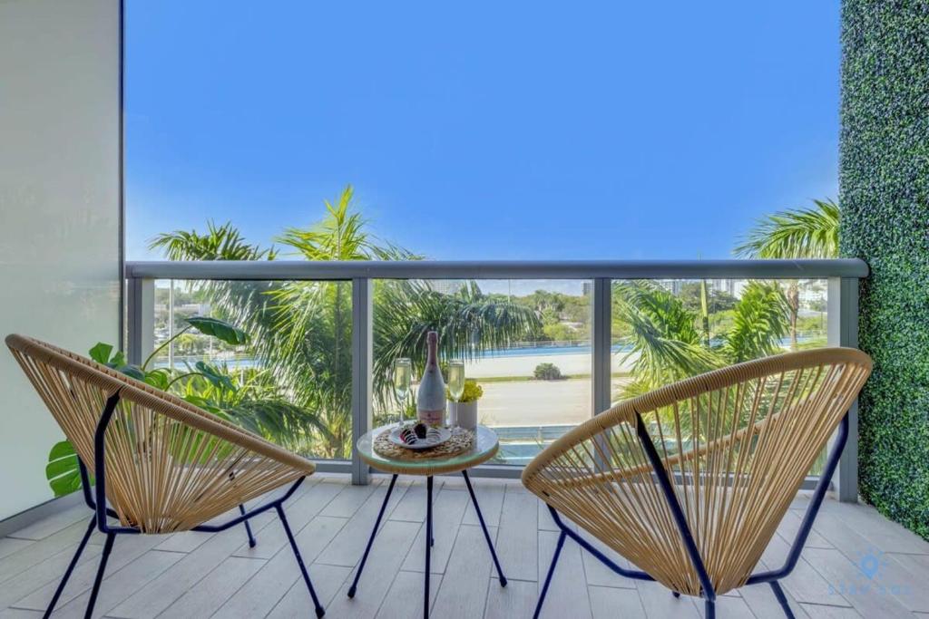 uma varanda com uma mesa e cadeiras num pátio em Tropical Apartment - Balcony - Resort, Pool - Gym em Hallandale Beach