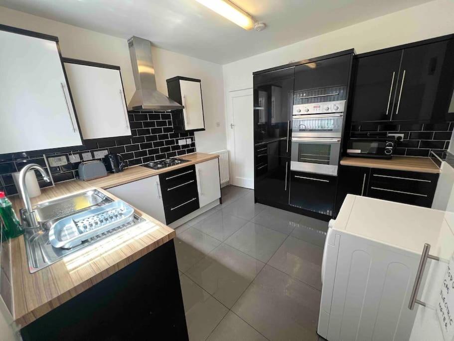 a kitchen with black and white cabinets and appliances at House in London near O2, Greenwich & Canary Wharf in Eltham