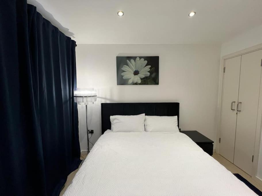 a bedroom with a large white bed with blue curtains at cosy and prime location in Sheffield