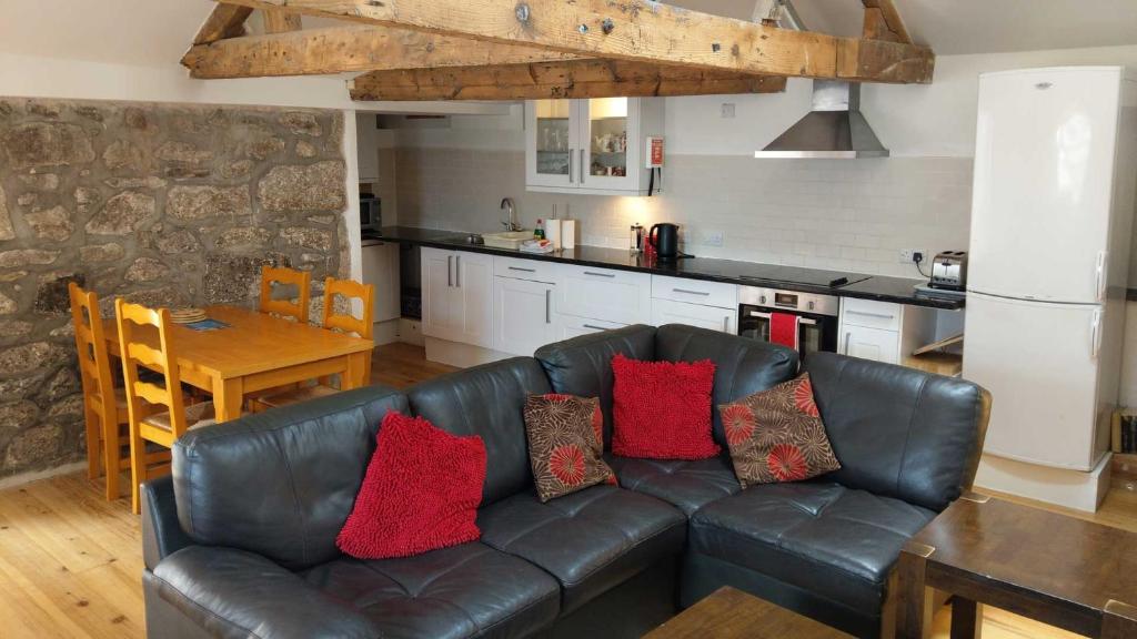 a living room with a leather couch and a kitchen at Sunny Corner - Bright, Spacious Apartment with Harbour Views - 102 in Penzance