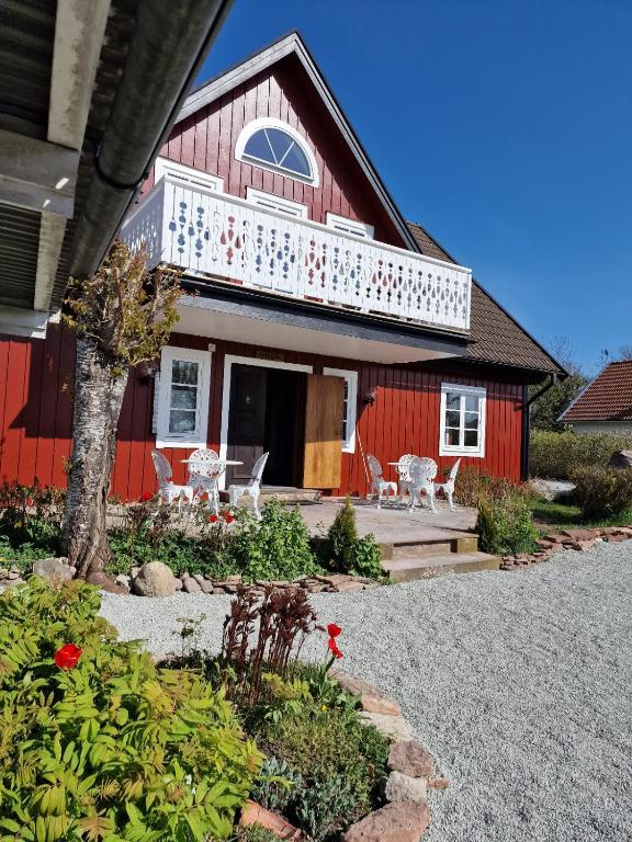 a red house with a white balcony and a yard at Annas Ställe B&B in Byxelkrok