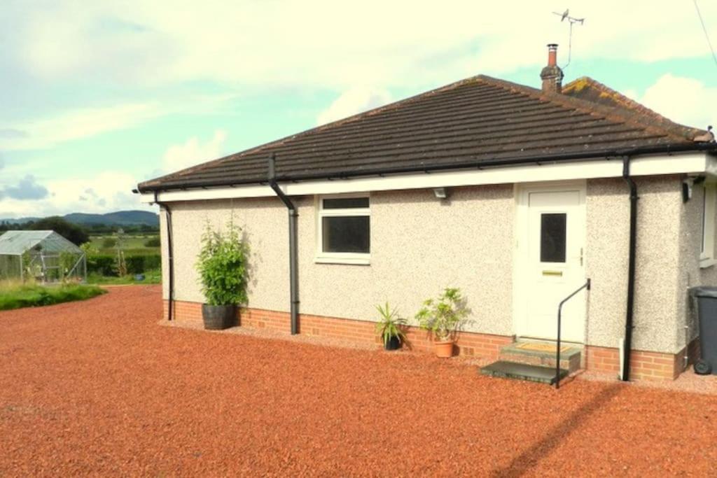 a white house with potted plants in front of it at Annexe Meadowbank Dumfries in Dumfries