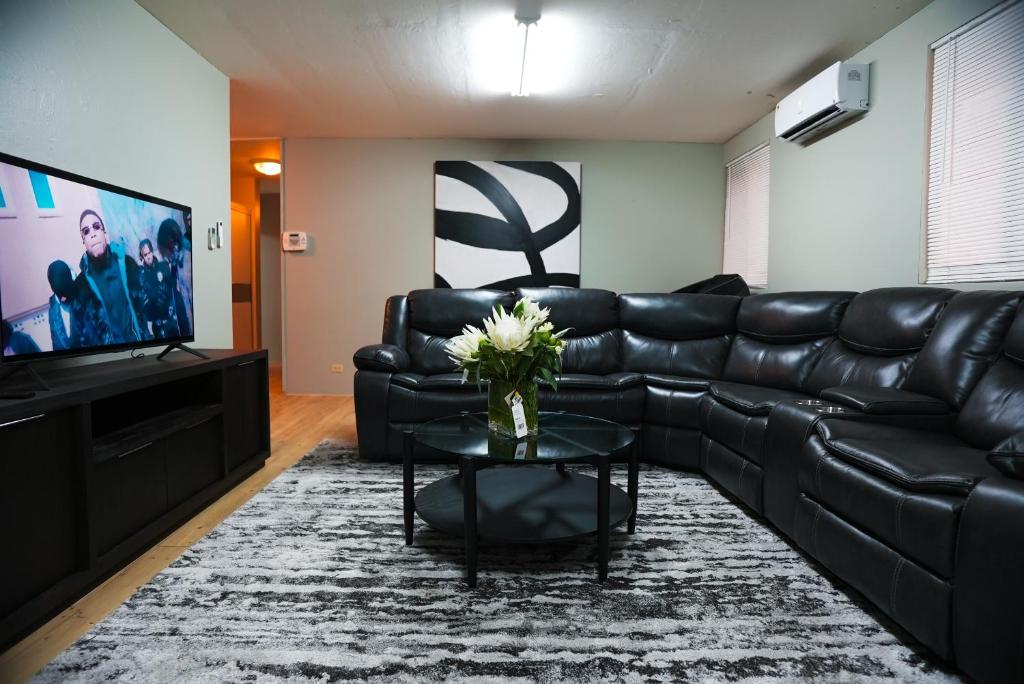 a living room with a black leather couch and a television at City Lights 143 in Tumon