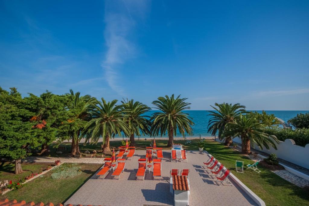 a row of orange chairs and palm trees and the ocean at Villa Lucia in Mattinata