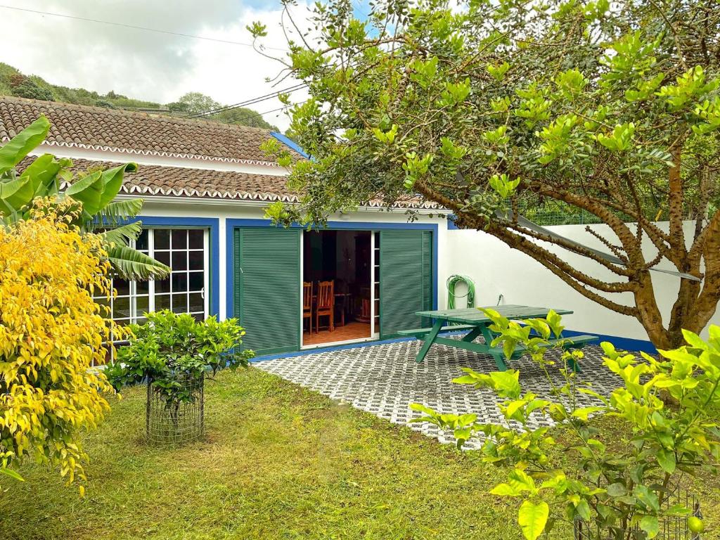 a green house with a picnic table in the yard at WelcomeBuddy - Casa Tia Néné - Green Glassyard in Lagoa