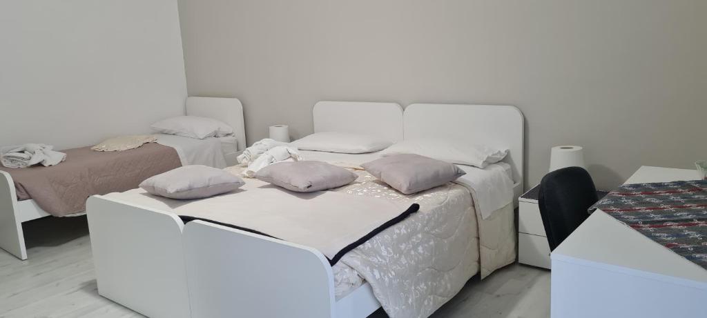 ein weißes Schlafzimmer mit 2 Betten und Kissen darauf in der Unterkunft CASA VACANZE PIAZZA GRAZIA in Caltanissetta