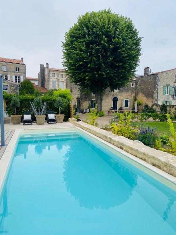 une grande piscine bleue dans une cour dans l'établissement The Old Stables, à Saint-Jean-dʼAngély