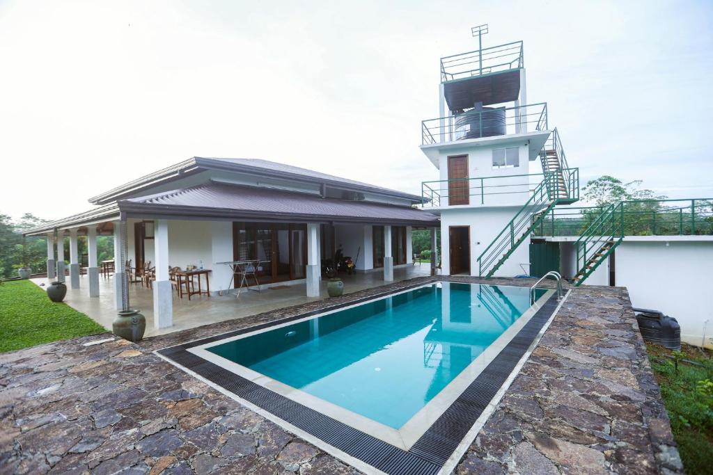 a swimming pool in front of a house at Plantation Villa in Baddegama