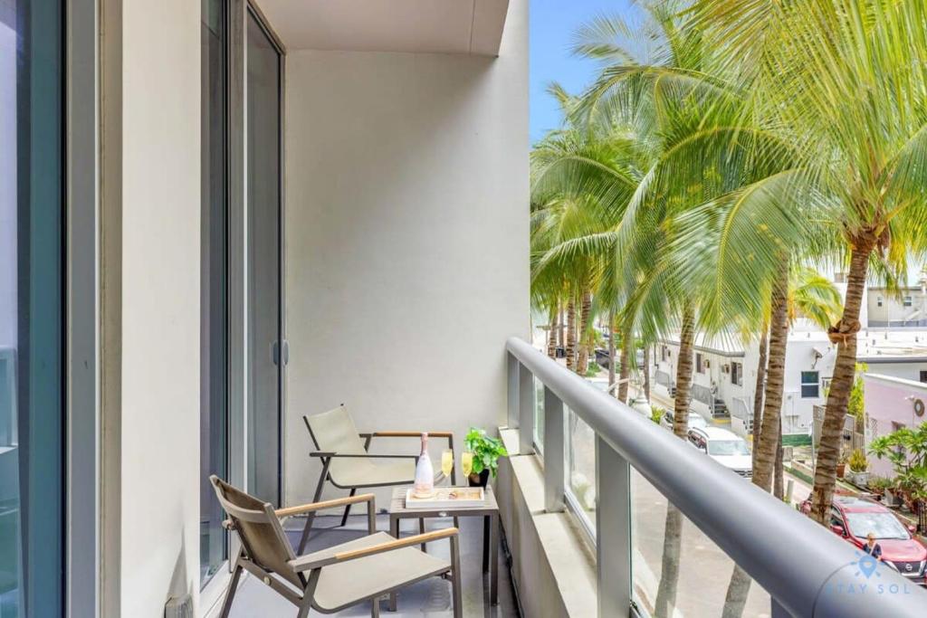 ハリウッドにあるModern Luxury Retreat: Rooftop Pool Ocean Viewsのヤシの木と椅子2脚付きのバルコニー
