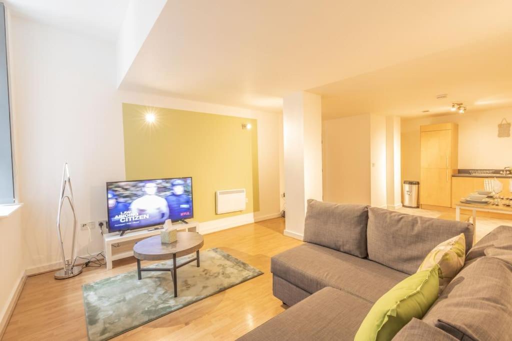 ein Wohnzimmer mit einem Sofa und einem TV in der Unterkunft Cosy, Modern City Centre Apartment Free Parking in Leicester