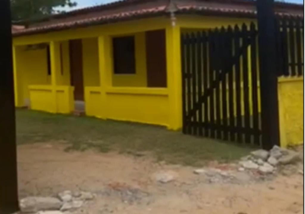 uma casa amarela com uma cerca em frente em Casa na em moitas de Amontada em Praia de Moitas