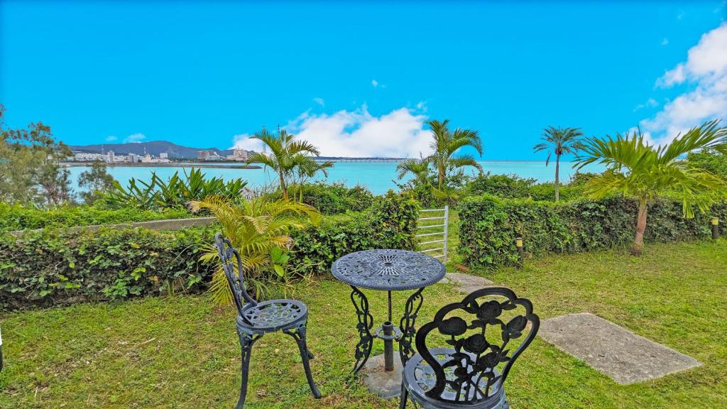 two chairs and a table with a view of the ocean at beach house Cg7p in Okinawa City
