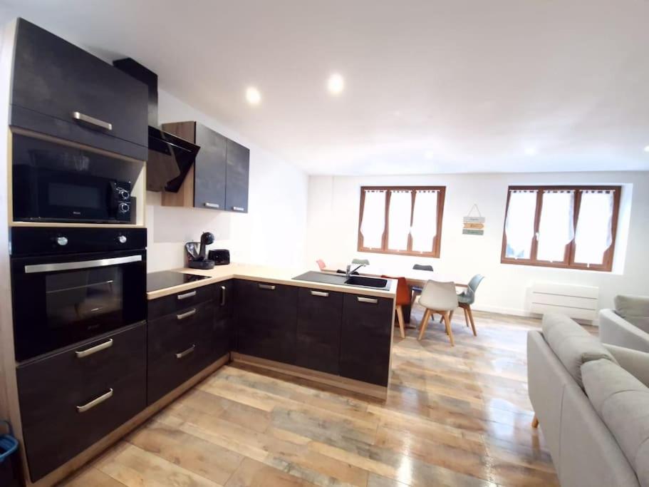 a kitchen with black cabinets and a living room at Grande et belle maison: 8 pers-4 chb-5 lits-wifi in Issoudun