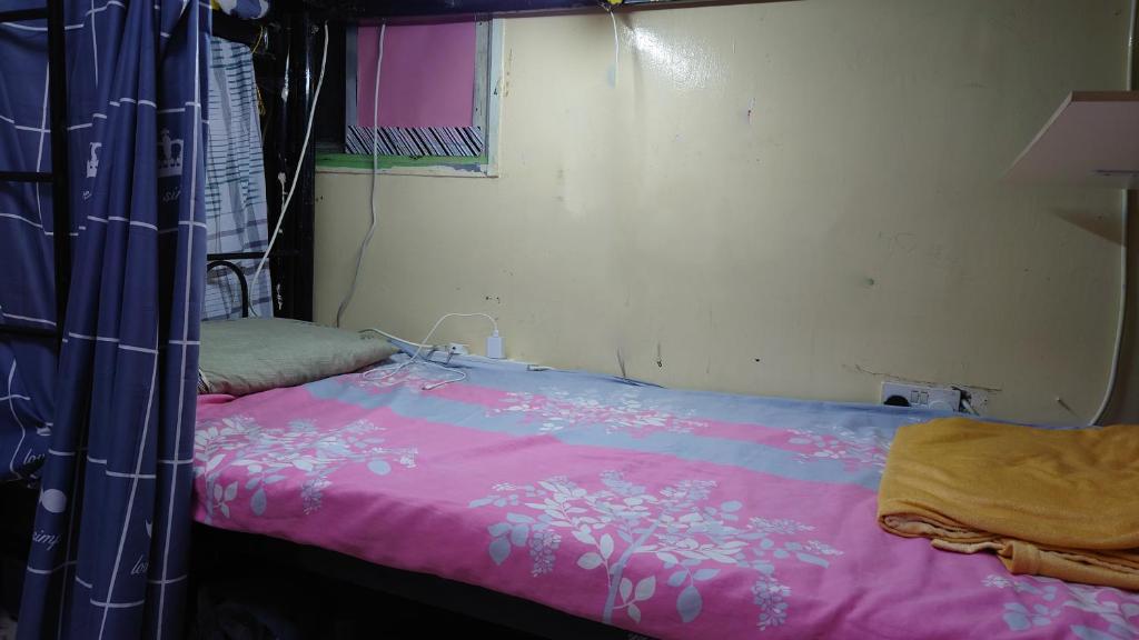 - une chambre avec un lit et une couverture rose dans l'établissement White Moon Men's Hostel, à Dubaï