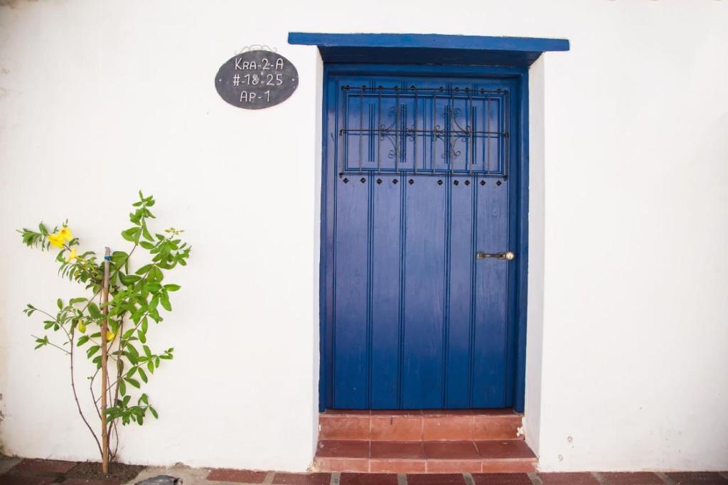 Apartamento Familiar Puerta Azul في مومبوس: باب ازرق في جدار ابيض فيه نبات