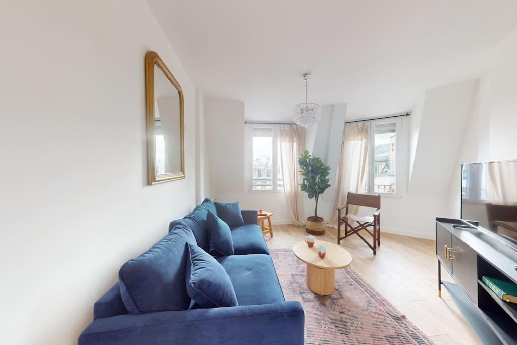 un salon avec un canapé bleu et une table dans l'établissement Helsinki, appartement atypique, à Reims
